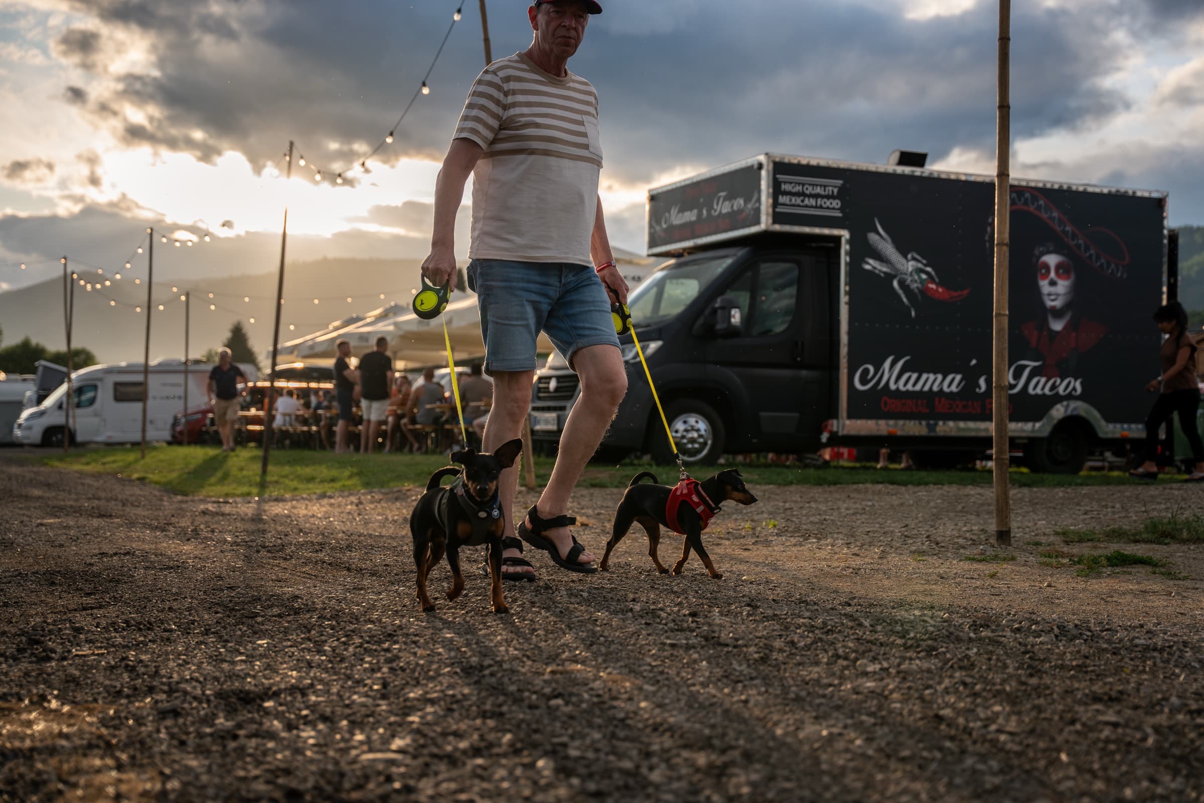 Abendliche Szene am Eventcamping: Gast mit Hunden vor dramatischem Himmel